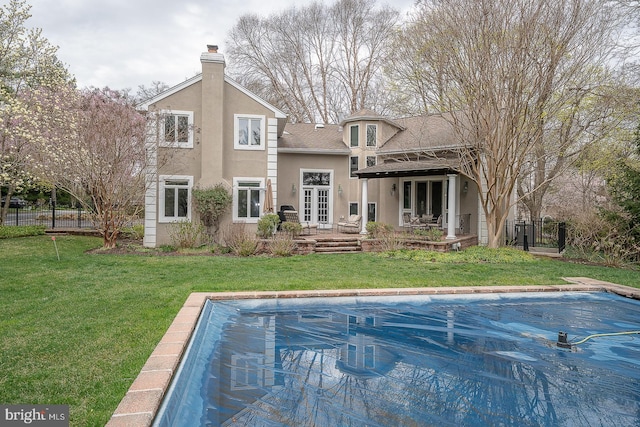 back of property featuring a fenced in pool, a yard, stucco siding, and fence
