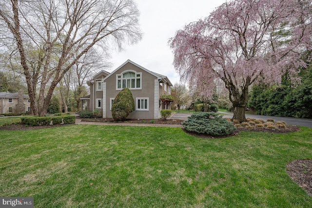 traditional-style home featuring a front yard and stucco siding