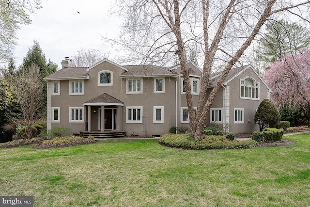 colonial house featuring a chimney, stucco siding, and a front lawn