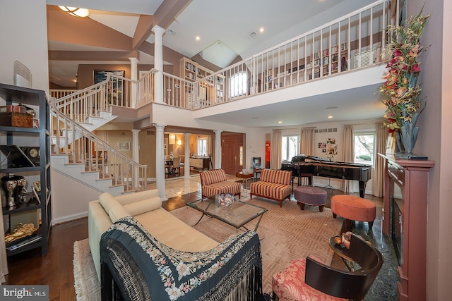 living room with a towering ceiling, baseboards, stairs, decorative columns, and wood finished floors