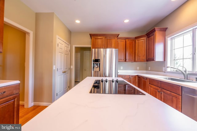 kitchen with brown cabinetry, recessed lighting, appliances with stainless steel finishes, and a sink