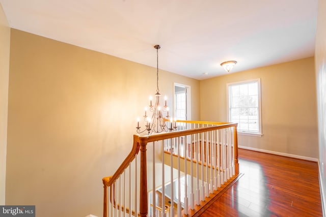 hall featuring an upstairs landing, a chandelier, baseboards, and wood finished floors