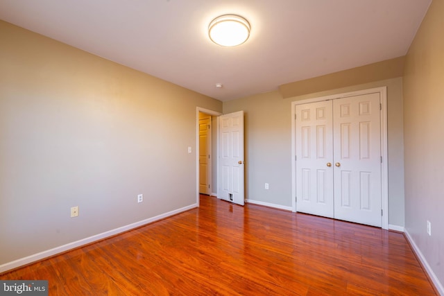 unfurnished bedroom featuring a closet, baseboards, and wood finished floors