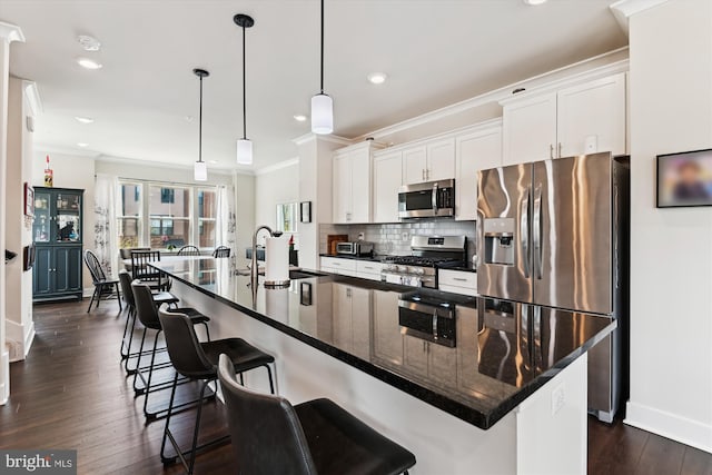 kitchen featuring baseboards, a sink, crown molding, white cabinetry, and stainless steel appliances