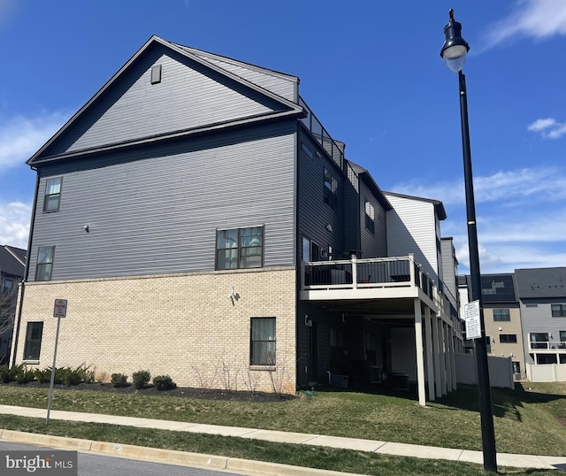 view of home's exterior with a yard, brick siding, and a deck