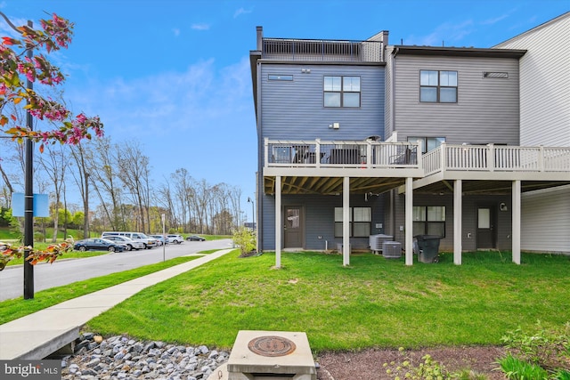 rear view of property with central air condition unit and a lawn