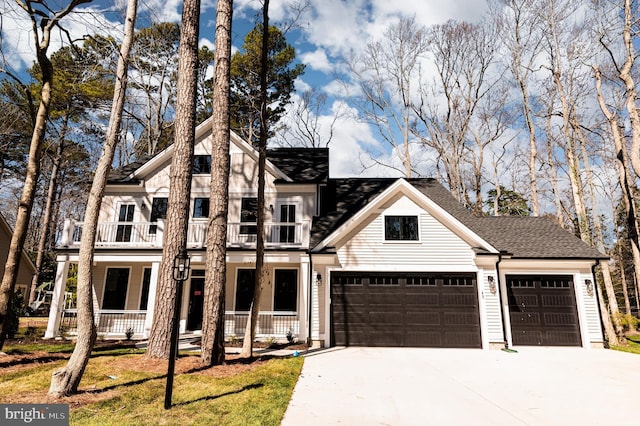 view of front of home featuring a balcony, an attached garage, concrete driveway, covered porch, and a shingled roof