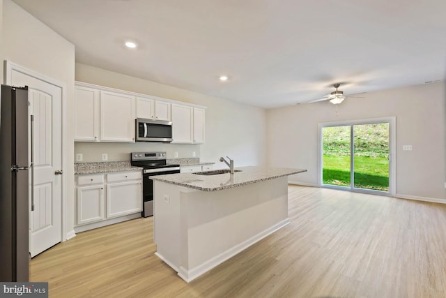 kitchen featuring ceiling fan, light stone counters, white cabinets, stainless steel appliances, and a sink