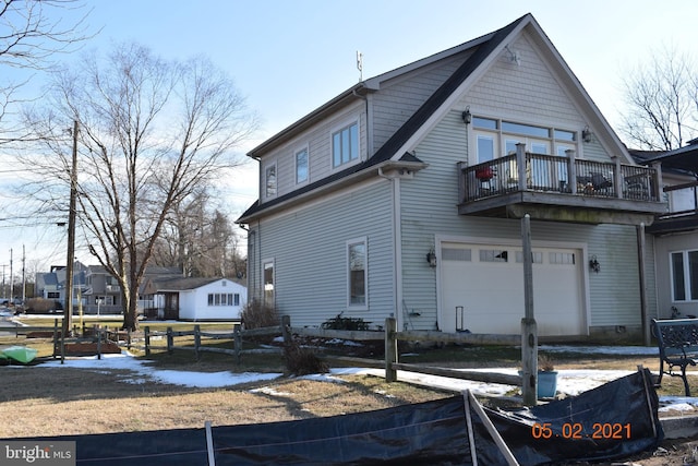 back of property featuring fence, a garage, and a balcony