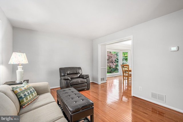living room featuring baseboards, light wood-style flooring, and visible vents