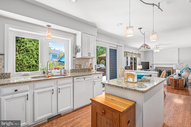 kitchen featuring ceiling fan, a sink, dishwasher, a center island, and light wood-type flooring