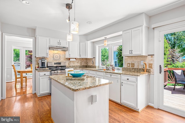 kitchen with white dishwasher, stainless steel range with gas cooktop, white cabinetry, and a wealth of natural light