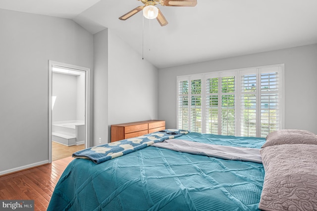 bedroom featuring ceiling fan, baseboards, ensuite bathroom, light wood-type flooring, and vaulted ceiling