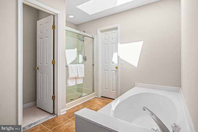 bathroom featuring a skylight, tile patterned floors, a shower stall, and a garden tub