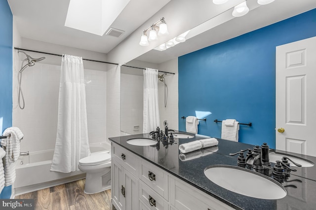 full bath featuring toilet, a sink, shower / tub combo with curtain, and wood finished floors