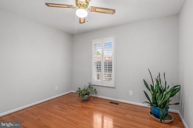 unfurnished room featuring baseboards, a ceiling fan, wood finished floors, and visible vents