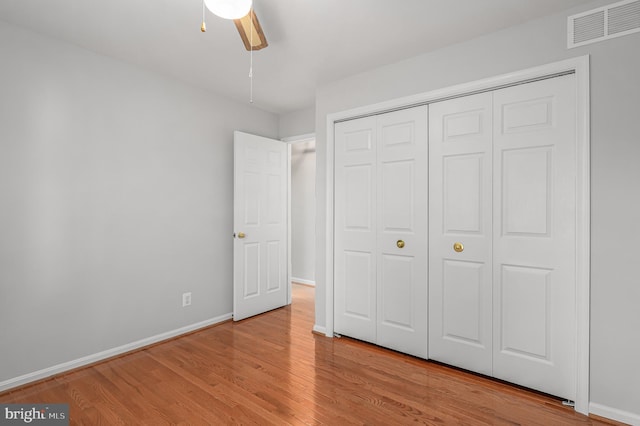 unfurnished bedroom with a ceiling fan, baseboards, wood finished floors, visible vents, and a closet