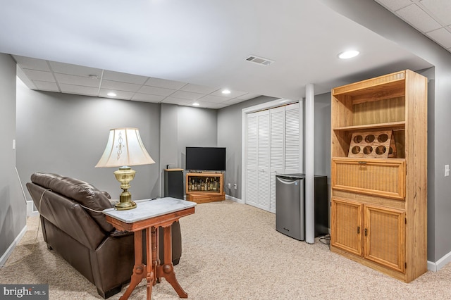 living area featuring baseboards, light carpet, a drop ceiling, and visible vents
