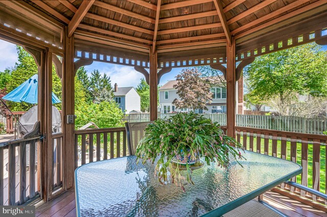 wooden terrace with fence, outdoor dining space, a gazebo, and a residential view