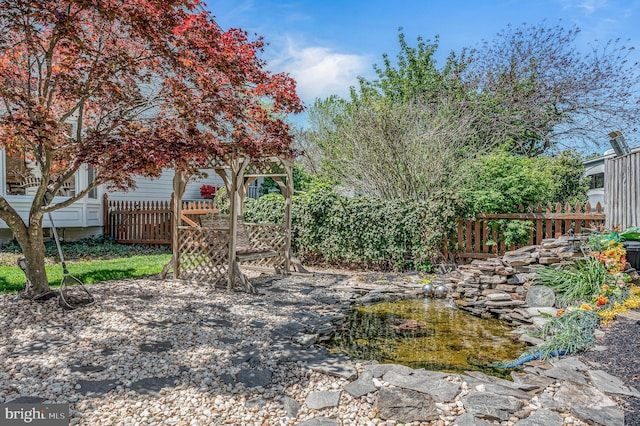 view of yard featuring a small pond and fence