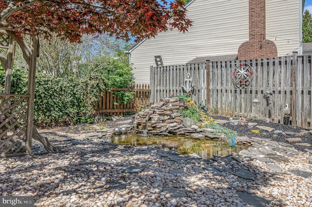 view of yard featuring fence and a small pond