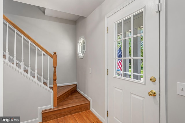 foyer with stairway, baseboards, and wood finished floors