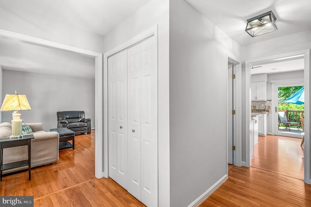corridor featuring baseboards and light wood finished floors