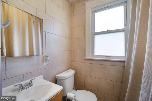 bathroom with vanity, tile walls, toilet, and a healthy amount of sunlight