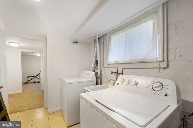 laundry room featuring separate washer and dryer, light tile patterned flooring, laundry area, light colored carpet, and a sink