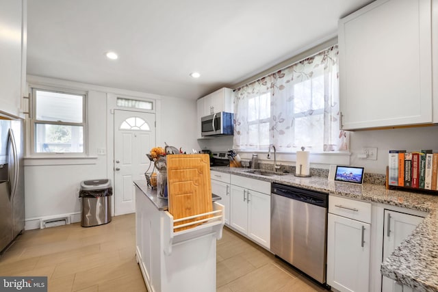 kitchen featuring appliances with stainless steel finishes, a sink, white cabinetry, and a healthy amount of sunlight