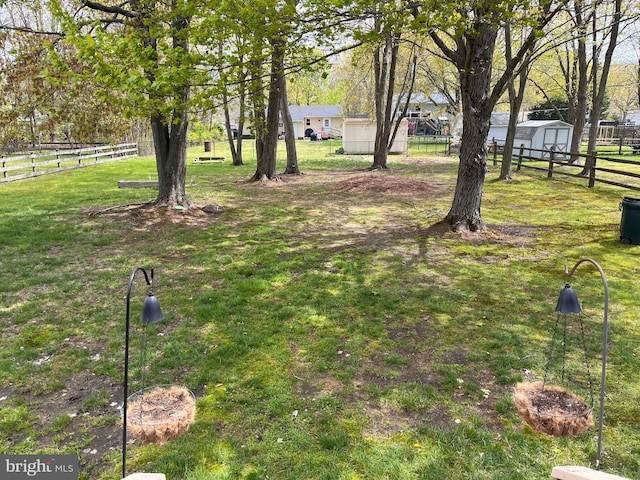 view of yard featuring an outdoor structure, fence, and a storage shed