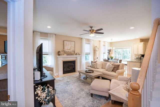 living room featuring a glass covered fireplace, light wood-style flooring, recessed lighting, and ceiling fan
