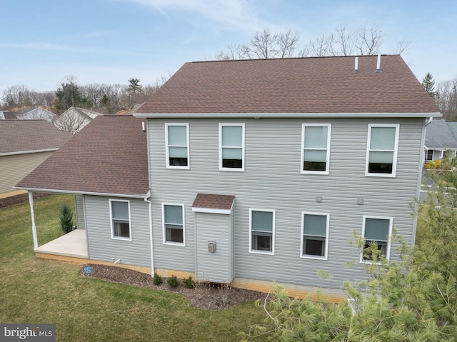 back of property featuring a yard and roof with shingles