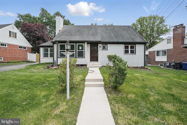 505 N Naylor St, Alexandria, VA 22304 - view of front of property featuring a front yard, brick siding, a chimney, roof with shingles, and central AC unit