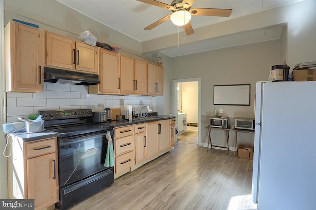 kitchen featuring black range with electric stovetop, under cabinet range hood, light brown cabinetry, and freestanding refrigerator