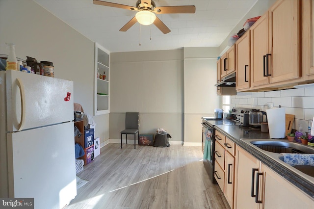 kitchen with light wood-type flooring, under cabinet range hood, electric stove, dark countertops, and freestanding refrigerator