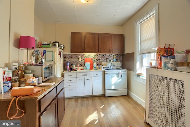 kitchen featuring light countertops, brown cabinets, light wood-style floors, backsplash, and electric range