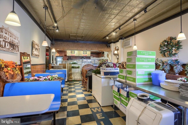 kitchen featuring tile patterned floors, a wainscoted wall, brick wall, and rail lighting