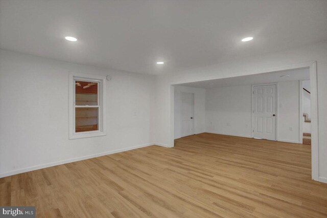 empty room with light wood finished floors, recessed lighting, stairs, and baseboards