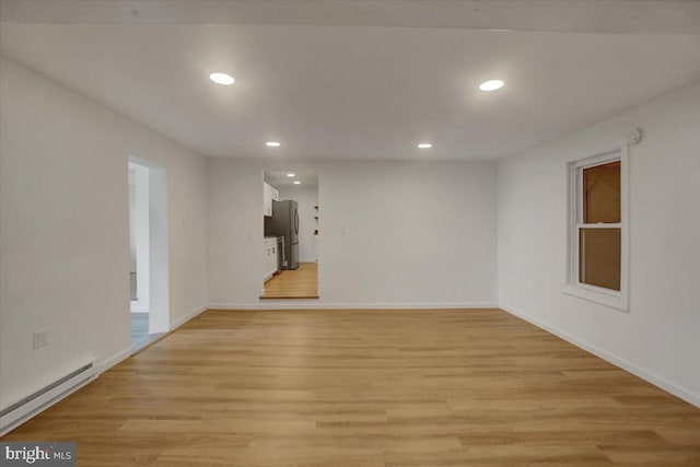 spare room featuring recessed lighting, baseboards, light wood finished floors, and a baseboard radiator
