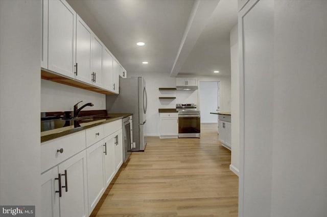 kitchen with under cabinet range hood, appliances with stainless steel finishes, light wood-style flooring, and white cabinets