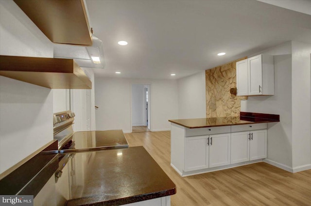 kitchen featuring a peninsula, electric range, dark countertops, and light wood finished floors