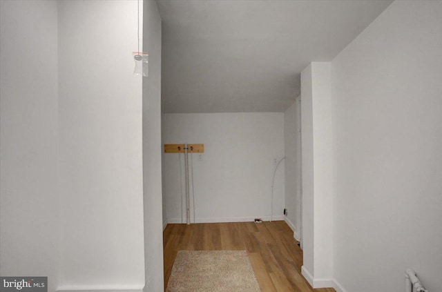 hallway featuring baseboards, wood finished floors, and radiator heating unit