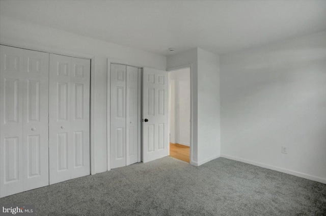 unfurnished bedroom featuring baseboards, carpet, and multiple closets