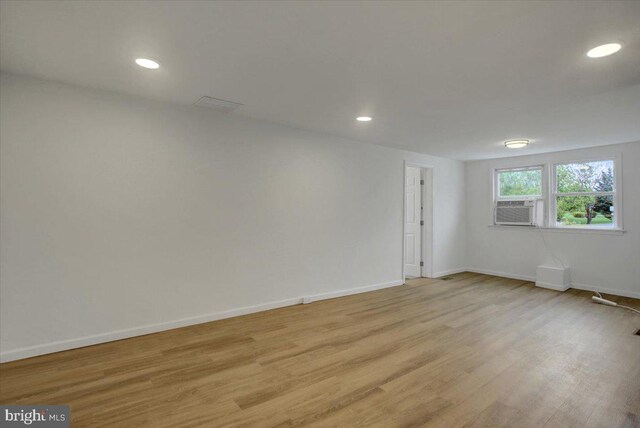 empty room featuring recessed lighting, cooling unit, baseboards, and light wood-style floors