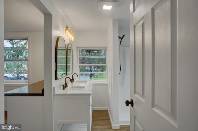 full bathroom featuring baseboards, walk in shower, wood finished floors, and vanity