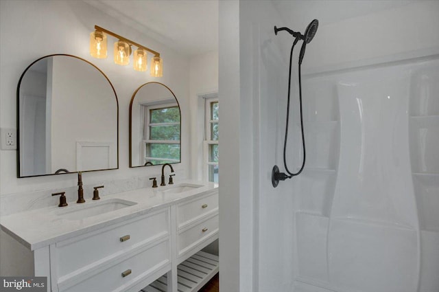 bathroom with a sink, a shower, and double vanity