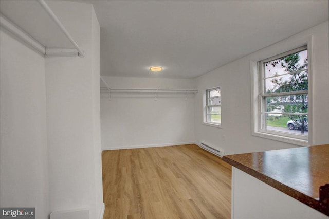spacious closet featuring light wood finished floors and baseboard heating