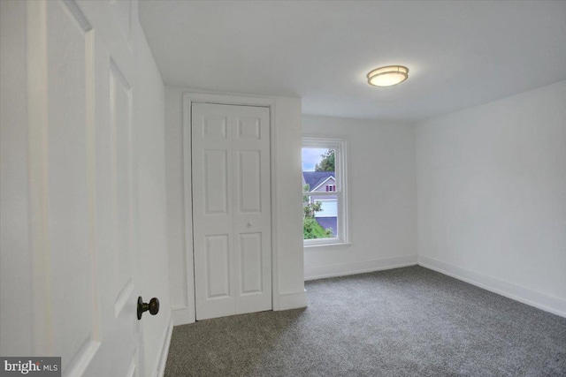 carpeted empty room featuring baseboards