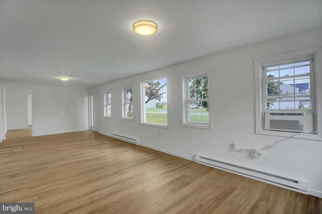unfurnished room with light wood-style flooring, cooling unit, and baseboard heating